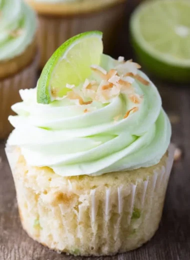 Coconut cupcakes topped with lime buttercream frosting on a decorative plate