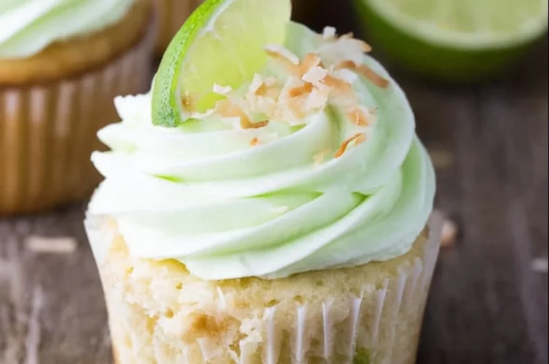 Coconut cupcakes topped with lime buttercream frosting on a decorative plate