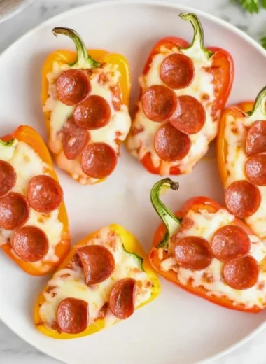 Pizza stuffed mini peppers served on a plate with fresh herbs.