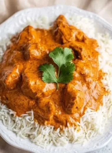 Delicious butter chicken served with rice and naan on a wooden table