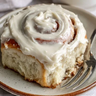 Freshly baked cinnamon rolls with icing on a wooden table