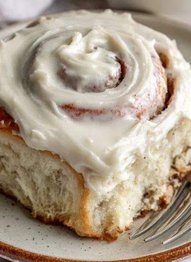 Freshly baked cinnamon rolls with icing on a wooden table
