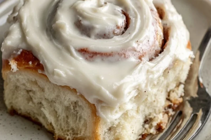 Freshly baked cinnamon rolls with icing on a wooden table