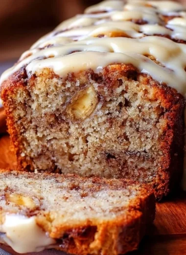 Slice of easy cinnamon roll banana bread with swirls of cinnamon and icing