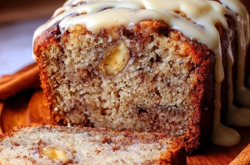 Slice of easy cinnamon roll banana bread with swirls of cinnamon and icing