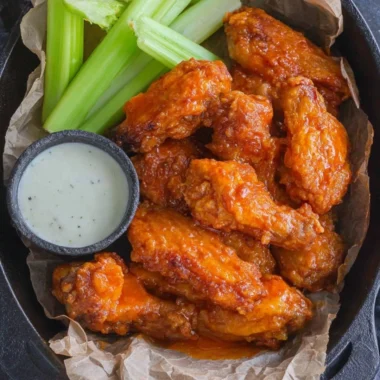 Plate of homemade buffalo wings with spicy sauce and celery sticks