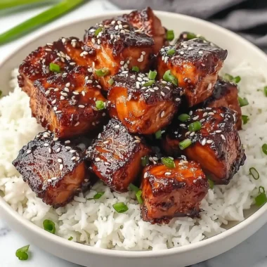 Honey garlic salmon bites bowl garnished with fresh herbs and served with rice