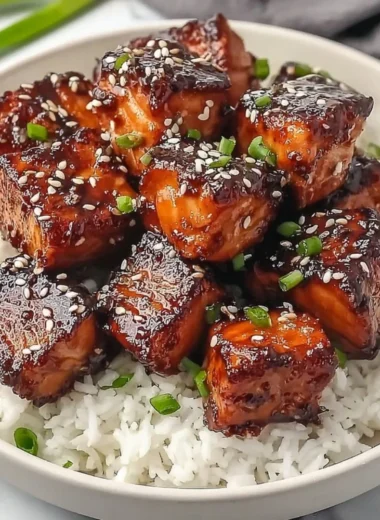 Honey garlic salmon bites bowl garnished with fresh herbs and served with rice