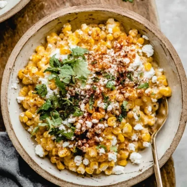 Baked Mexican street corn casserole in a serving dish, topped with cheese and herbs.