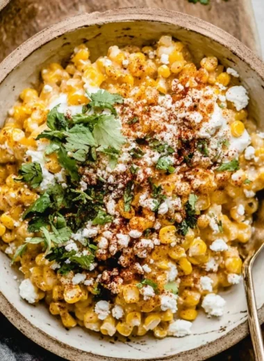 Baked Mexican street corn casserole in a serving dish, topped with cheese and herbs.