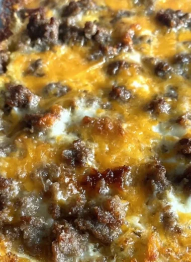 Sausage Hashbrown Breakfast Casserole baked in a dish, topped with cheese and herbs