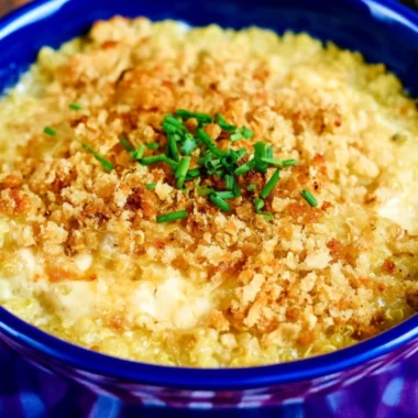 Bowl of cheesy quinoa mac and cheese topped with herbs and cheese