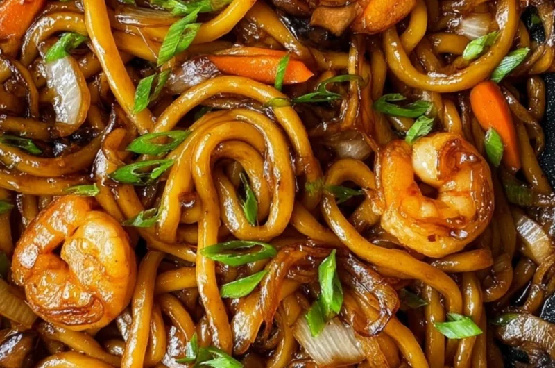 Delicious plate of Fried Udon topped with vegetables and sauce