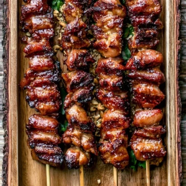 Grilled Thai Coconut Chicken Skewers on a platter with fresh herbs and lime.