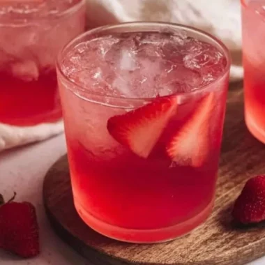 Glass of refreshing strawberry iced tea with fresh strawberries and mint leaves