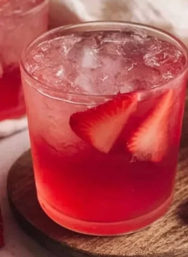 Glass of refreshing strawberry iced tea with fresh strawberries and mint leaves