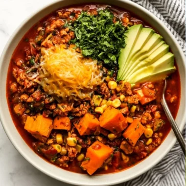 A bowl of sweet potato turkey chili topped with cilantro and served with crusty bread.