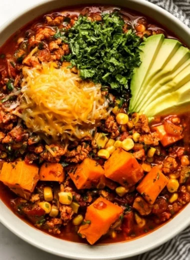 A bowl of sweet potato turkey chili topped with cilantro and served with crusty bread.
