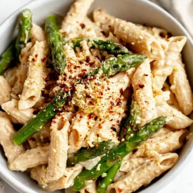 Vegan lemon white bean pasta garnished with fresh herbs.