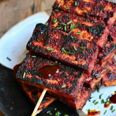 Vegan Sweet and Spicy BBQ Tofu served on a plate with garnishes