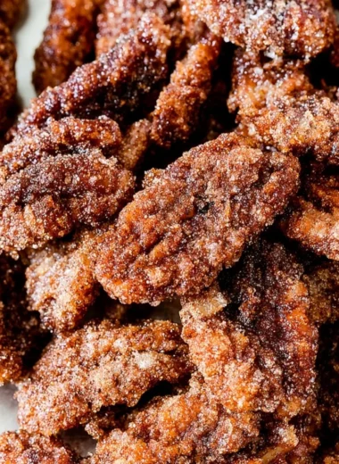 Cinnamon sugar candied pecans in a bowl, a sweet snack or dessert topping.
