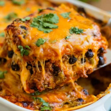 Cozy beef enchilada casserole topped with cheese and fresh ingredients