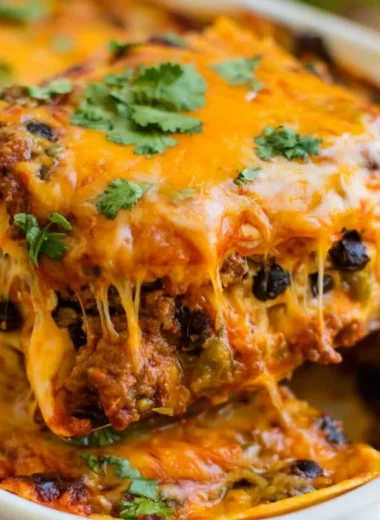 Cozy beef enchilada casserole topped with cheese and fresh ingredients