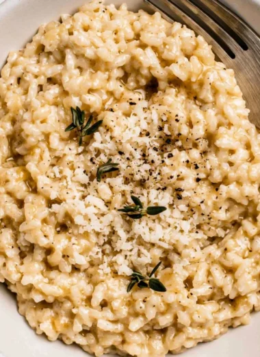 Plate of creamy risotto garnished with herbs and grated cheese