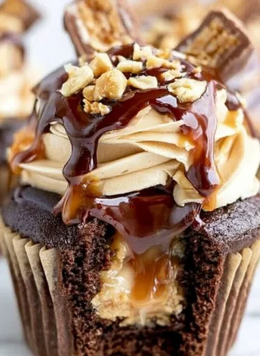 Delicious Snickers Cupcakes topped with chocolate, caramel, and peanuts