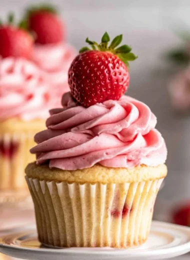 Delicious strawberry jam cupcakes topped with frosting and fresh strawberries.
