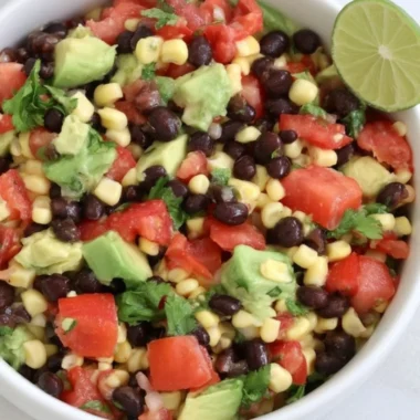 A colorful plate of dense bean salad with fresh vegetables and herbs