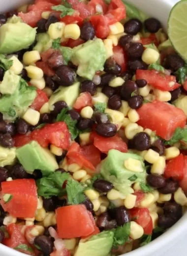 A colorful plate of dense bean salad with fresh vegetables and herbs