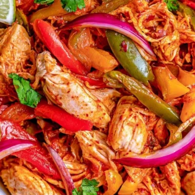 Bowl of crockpot chicken fajitas with colorful peppers and onions.