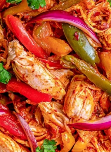 Bowl of crockpot chicken fajitas with colorful peppers and onions.